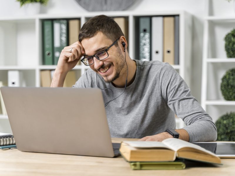 medium-shot-smiley-guy-studying-with-his-laptop